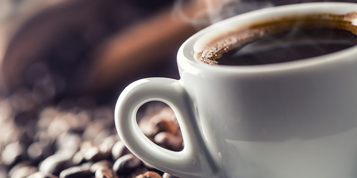 Cup of black coffee with beans on wooden table I benefici della caffeina nello sport: il caffè è alleato degli sportivi! - COFF-E
